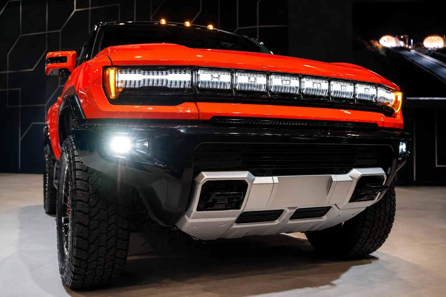 Front view of a rugged Hummer pickup truck with illuminated headlights and aggressive off-road styling, showcased indoors and representing the type of vehicle that benefits from expert Hummer service & repair in UAE to maintain peak performance and durability.