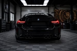 Rear view of a sleek BMW sports sedan inside a modern automotive facility, showcasing its distinctive BMW badge, illuminated taillights, and premium design. The professional setting reflects the high standards of a BMW workshop in Dubai, specializing in expert maintenance, diagnostics, performance upgrades, and luxury vehicle servicing.