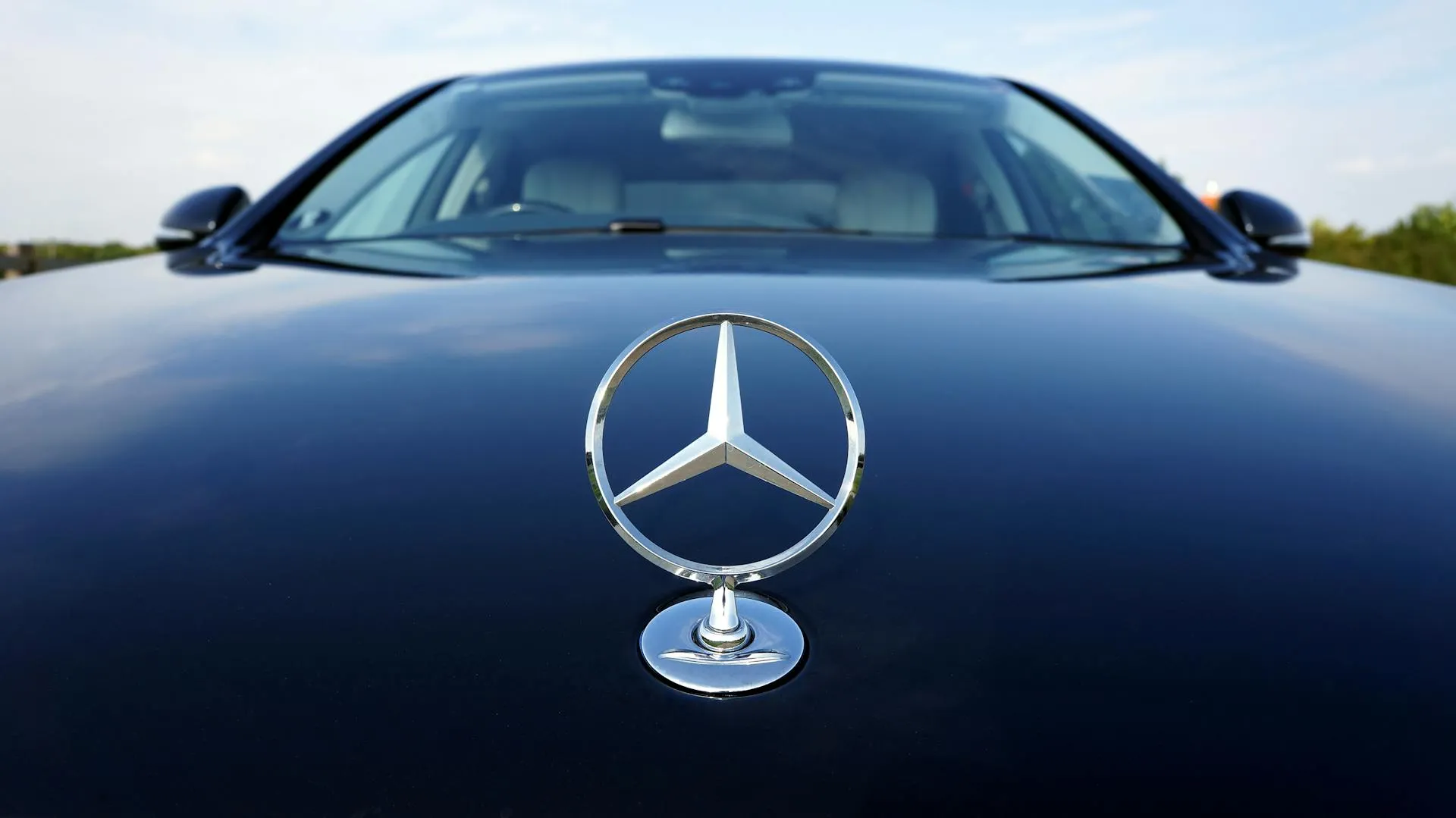 Close-up of the iconic Mercedes-Benz hood emblem on a luxury vehicle, showcasing the brand’s signature design and premium craftsmanship. The vehicle is presented in pristine condition, reflecting the high standards of service and attention to detail associated with a professional Mercedes garage in Al Quoz.