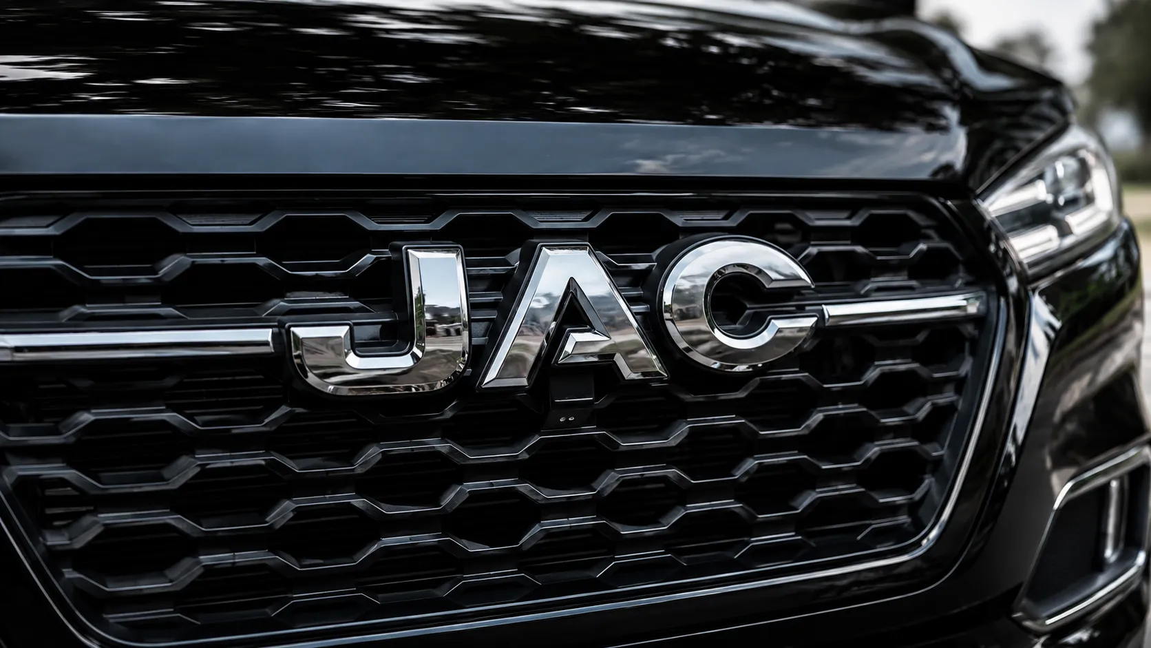 لقطة مقربة لشبكة JAC الأمامية ذات اللون الأحمر اللامع وشارة الكروم، والتي تعرض خدمة JAC الاحترافية والعناية بالمركبة.