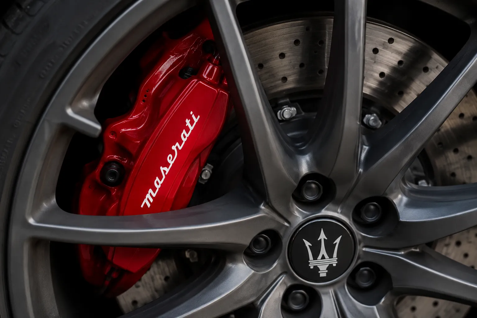 Close-up of a Maserati wheel with a red brake caliper, representing premium performance and Maserati suspension repair services.