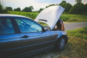 ركن السيارة على جانب الطريق مع فتح غطاء المحرك بعد توقف السيارة أثناء القيادة، حيث يقوم السائق بفحص المحرك بحثاً عن المشكلة.