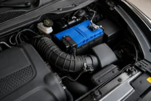 Close-up of a modern car engine bay featuring the battery, air intake, and surrounding components, illustrating a common issue where the battery dies after sitting for two days due to battery or electrical system problems.